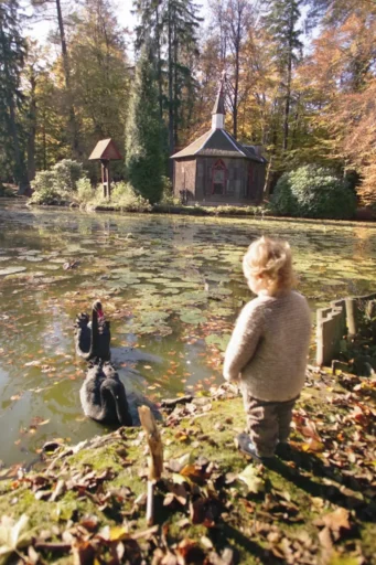 ein Kind steht an einem Teich