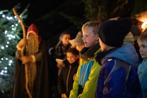 Kinder singen auf einem Weihnachtsmarkt im dunkeln